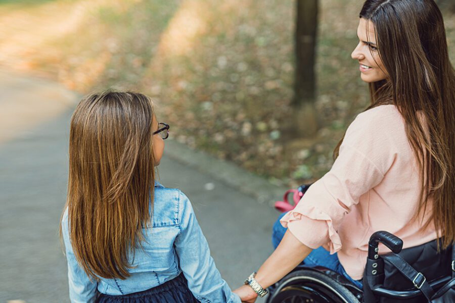 Mother in a wheelchair holding the hand of her daughter in the park