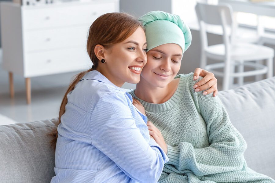 woman hugging a female friend with ovarian cancer in the couch.